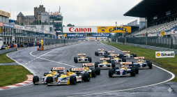 F1-Rennwagen beim Start auf dem Nürburgring bei nassem Wetter, mit Canon-Williams-Boliden und der Nürburg im Hintergrund. Historisches Motorsportbild.