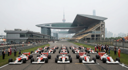 Reihe von klassischen McLaren-Honda Formel-1-Wagen mit Marlboro-Sponsoring auf einer Rennstrecke vor moderner Architektur von Shanghai, darunter der Oriental Pearl TV Tower.