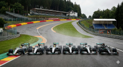 Sechs Mercedes F1-Autos stehen auf einer nassen Rennstrecke vor den Tribünen und Wäldern von Spa-Francorchamps in Belgien.