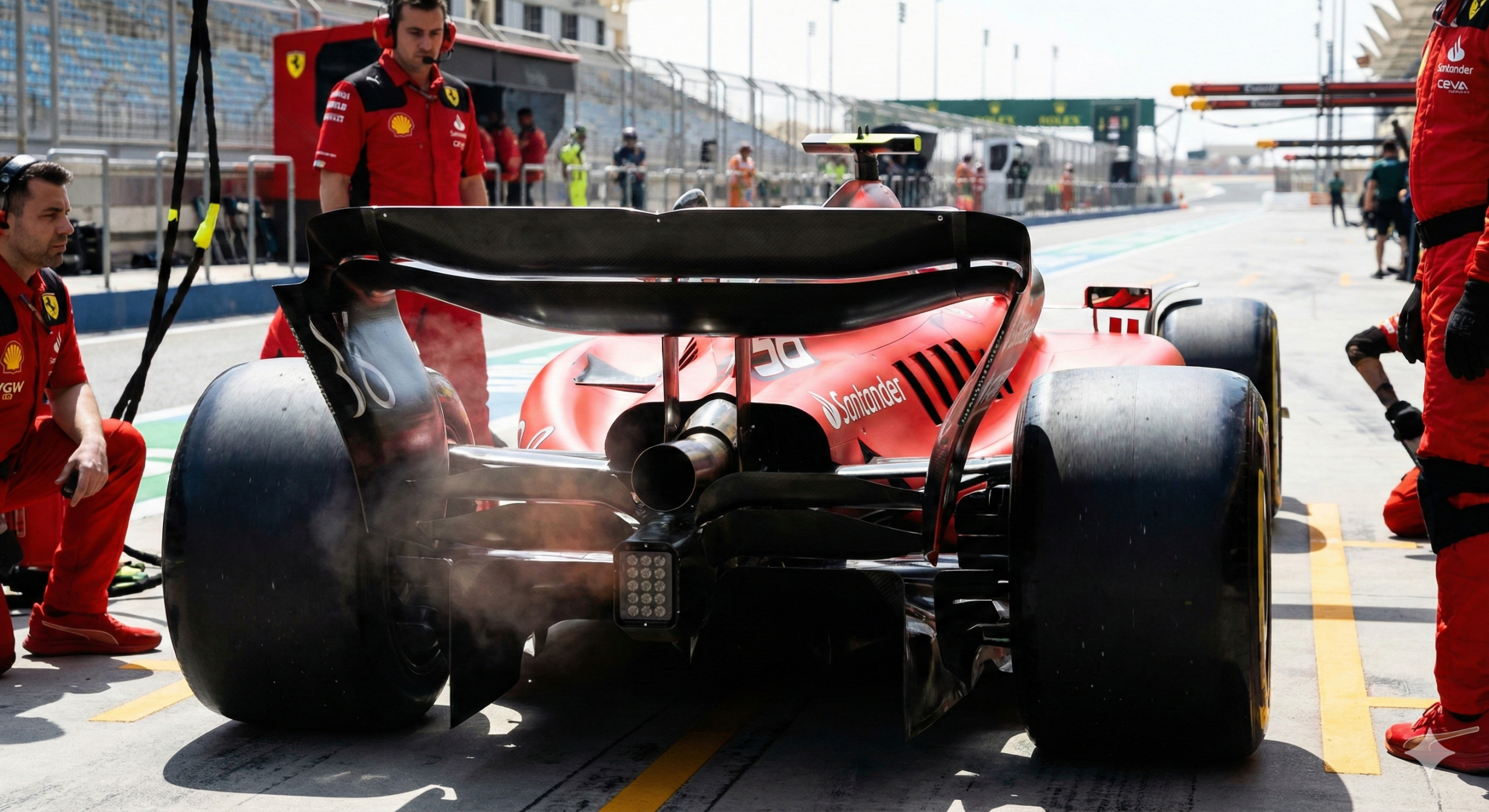Roter Ferrari Formel 1 Wagen in der Boxengasse mit Teammitgliedern und Dampf an den Hinterrädern während eines Grand Prix.